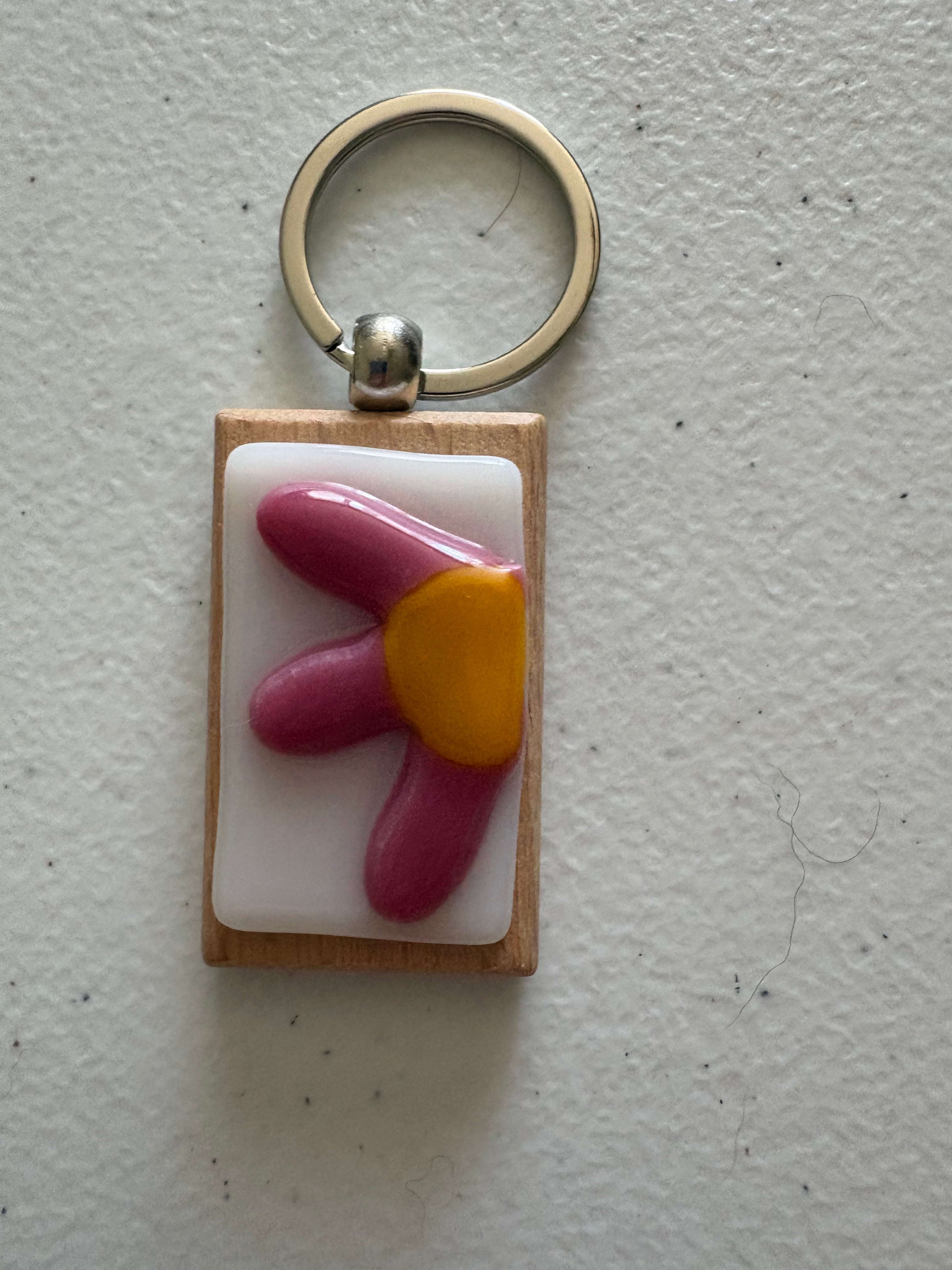 Pink rounded flower fused glass keychain with large yellow center on white glass tile with wood backing and silver key ring