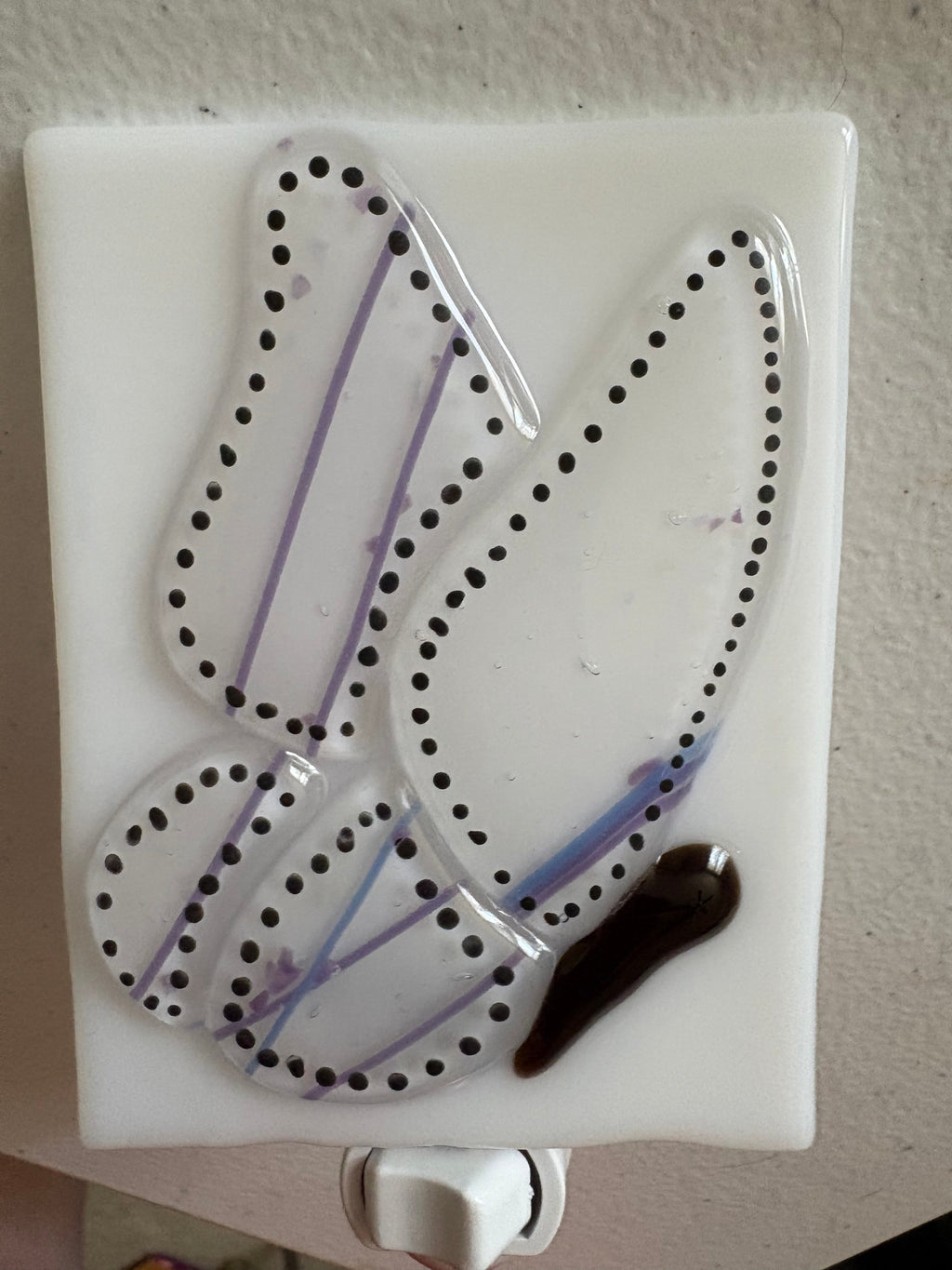Fused glass dragonfly nightlight illuminated on wall, showing wing silhouette